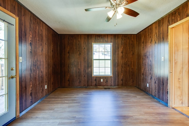 unfurnished room featuring light hardwood / wood-style flooring, wood walls, and plenty of natural light