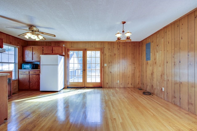 kitchen with light hardwood / wood-style flooring, white fridge, and wooden walls