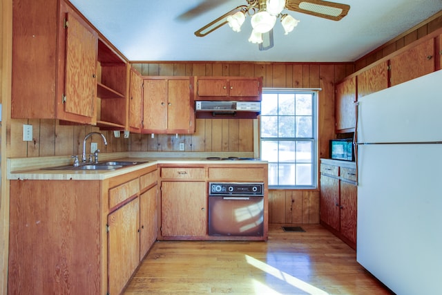 kitchen with light hardwood / wood-style flooring, wooden walls, black appliances, range hood, and sink