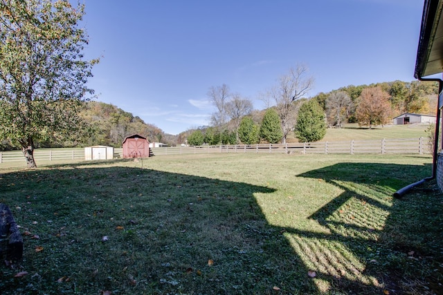 view of yard featuring a rural view, a shed, and a mountain view