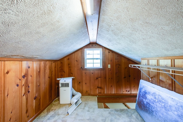 additional living space with light carpet, wood walls, a textured ceiling, and vaulted ceiling