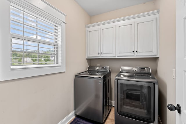 laundry area with independent washer and dryer, cabinets, and light tile patterned floors