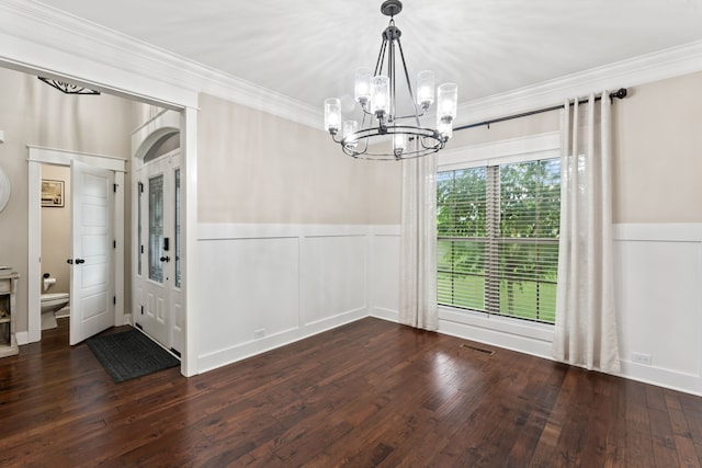 unfurnished dining area featuring an inviting chandelier, crown molding, and dark wood-type flooring