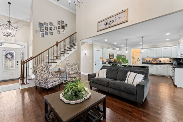 living room with a notable chandelier, ornamental molding, a high ceiling, and dark hardwood / wood-style flooring