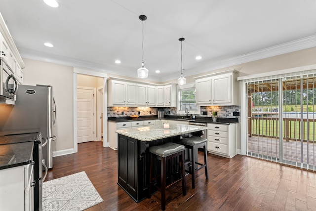 kitchen with stainless steel appliances, dark stone countertops, a center island, white cabinetry, and dark hardwood / wood-style flooring