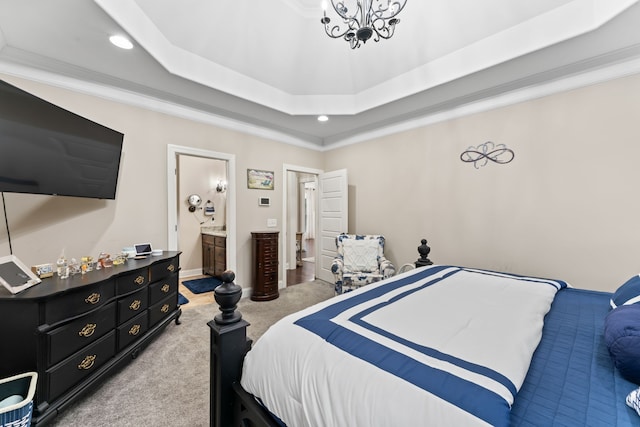 bedroom featuring ornamental molding, light carpet, a tray ceiling, and ensuite bath