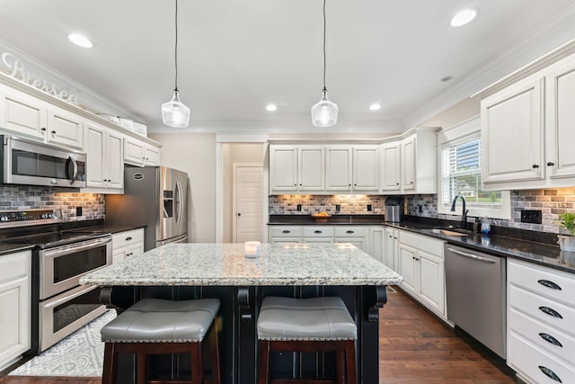 kitchen featuring a center island, stainless steel appliances, sink, and hanging light fixtures