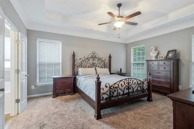 bedroom featuring ceiling fan, a raised ceiling, ornamental molding, and light colored carpet