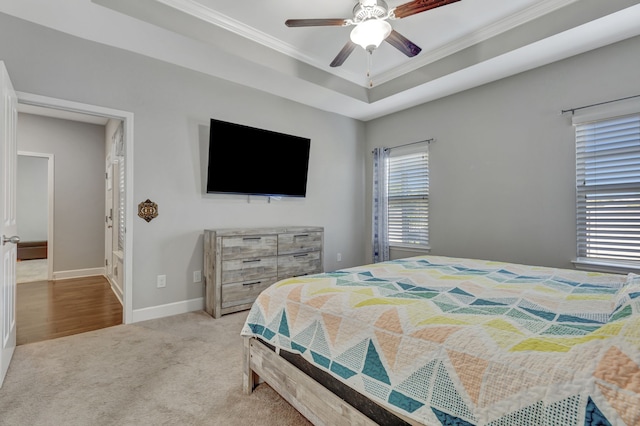 bedroom featuring crown molding, light colored carpet, a tray ceiling, and ceiling fan