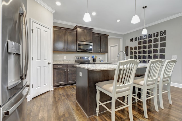 kitchen with a kitchen island with sink, appliances with stainless steel finishes, dark hardwood / wood-style floors, and hanging light fixtures