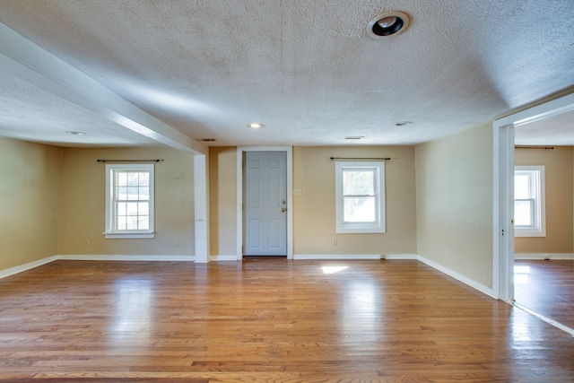 empty room with light hardwood / wood-style flooring and a textured ceiling