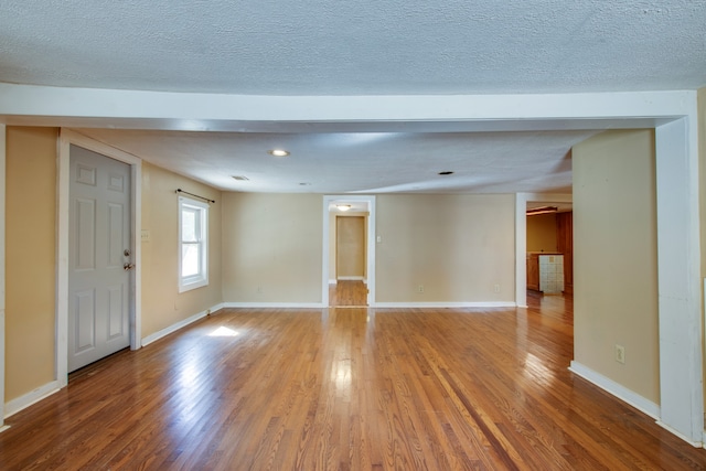 empty room featuring a textured ceiling and hardwood / wood-style floors