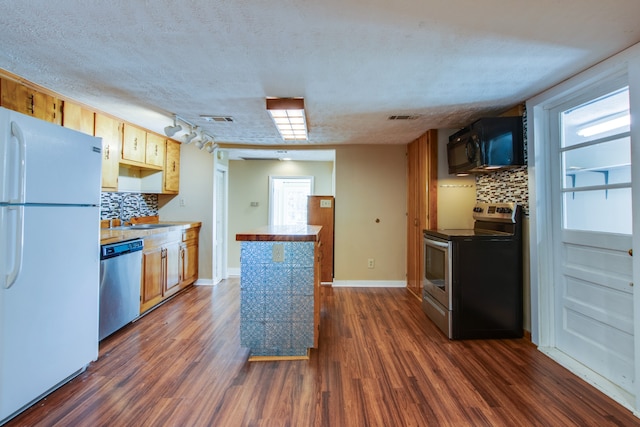 kitchen featuring sink, appliances with stainless steel finishes, dark hardwood / wood-style floors, and backsplash