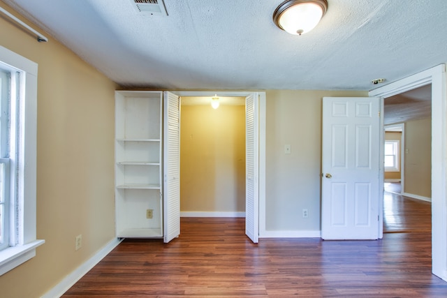 unfurnished bedroom featuring dark hardwood / wood-style floors and a textured ceiling