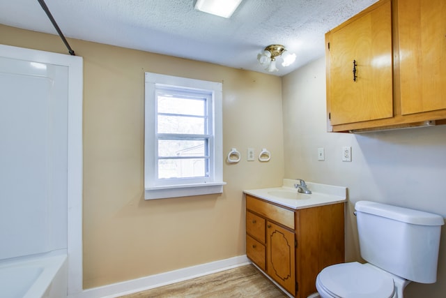 full bathroom featuring  shower combination, a textured ceiling, hardwood / wood-style floors, toilet, and vanity