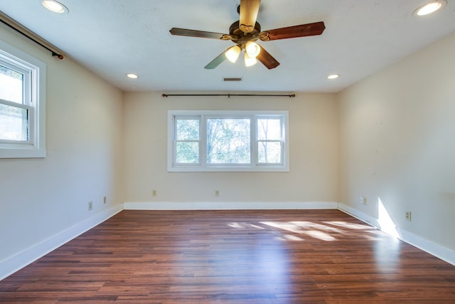 unfurnished room featuring a wealth of natural light, dark wood-type flooring, and ceiling fan