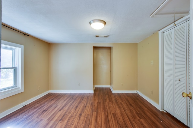 empty room with dark wood-type flooring and a textured ceiling