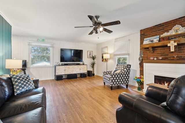 living room with light hardwood / wood-style flooring, ceiling fan, a fireplace, and a wealth of natural light