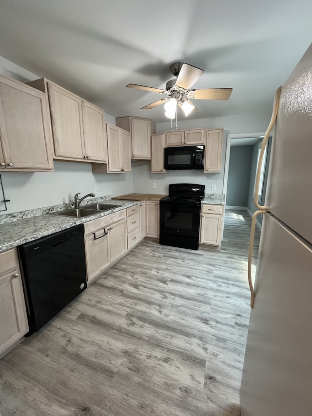 kitchen with black appliances, sink, light wood-type flooring, ceiling fan, and light stone counters