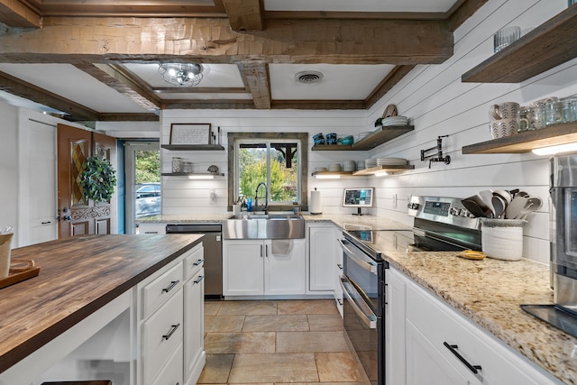 kitchen featuring beam ceiling, appliances with stainless steel finishes, sink, white cabinetry, and butcher block countertops