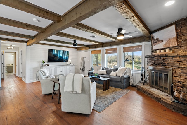 living room featuring beam ceiling, hardwood / wood-style flooring, a fireplace, and ceiling fan