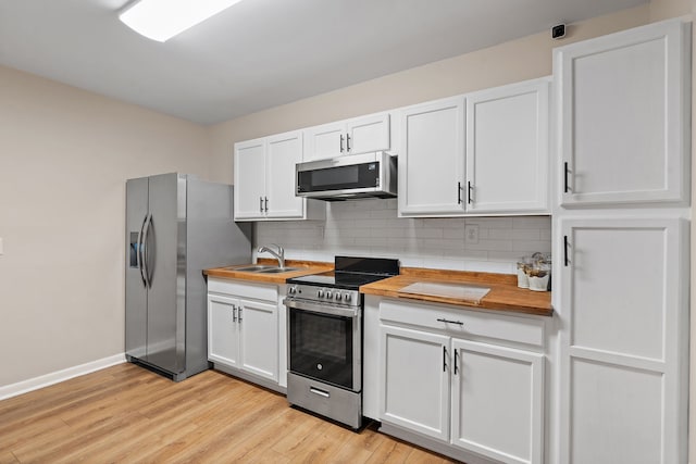 kitchen with sink, white cabinetry, light wood-type flooring, appliances with stainless steel finishes, and tasteful backsplash