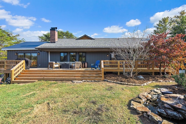 rear view of house with a deck and a yard