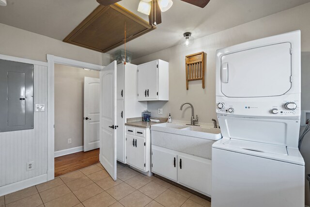 laundry room featuring light tile patterned flooring, electric panel, stacked washer and clothes dryer, and sink