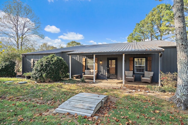 rear view of property featuring covered porch and a lawn