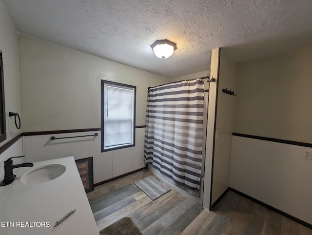 bathroom featuring vanity, a textured ceiling, walk in shower, and wood-type flooring