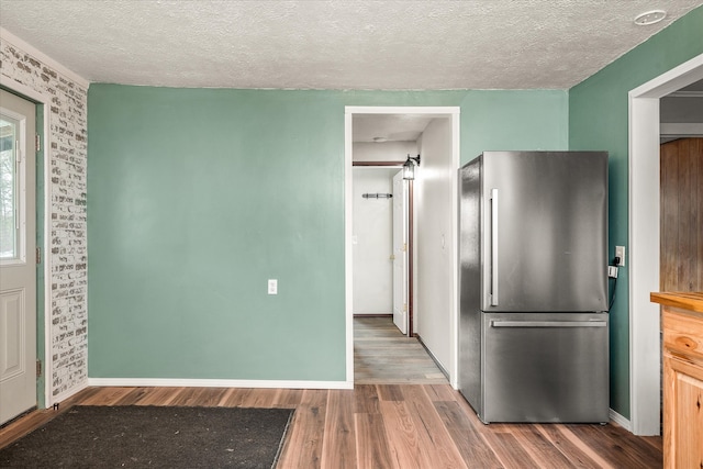 kitchen featuring a textured ceiling, wood-type flooring, and stainless steel refrigerator