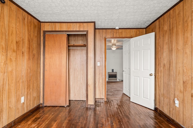 unfurnished bedroom with crown molding, dark hardwood / wood-style floors, a closet, and wood walls