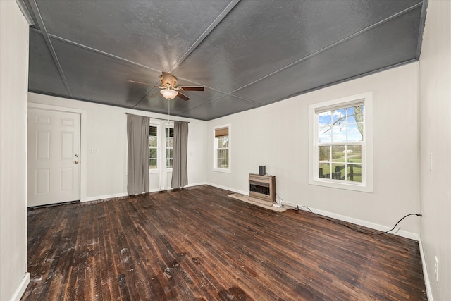 unfurnished living room featuring dark wood-type flooring, ceiling fan, a wood stove, and heating unit