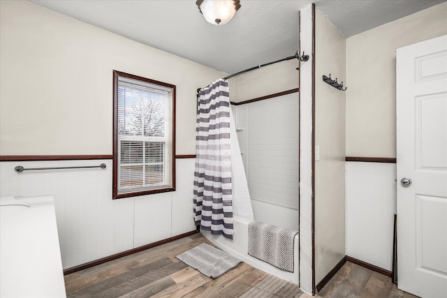 bathroom featuring a textured ceiling, shower / bath combination with curtain, and wood-type flooring