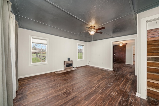 unfurnished living room with plenty of natural light, ceiling fan, heating unit, and dark hardwood / wood-style flooring