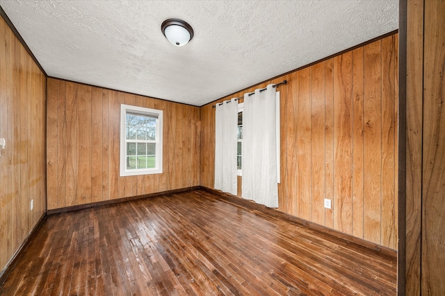 empty room with wood walls, a textured ceiling, and dark hardwood / wood-style flooring