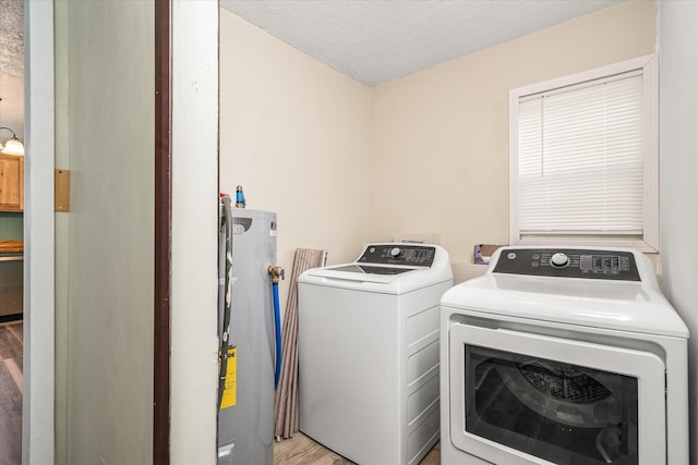 washroom featuring light wood-type flooring, a textured ceiling, water heater, and washing machine and clothes dryer