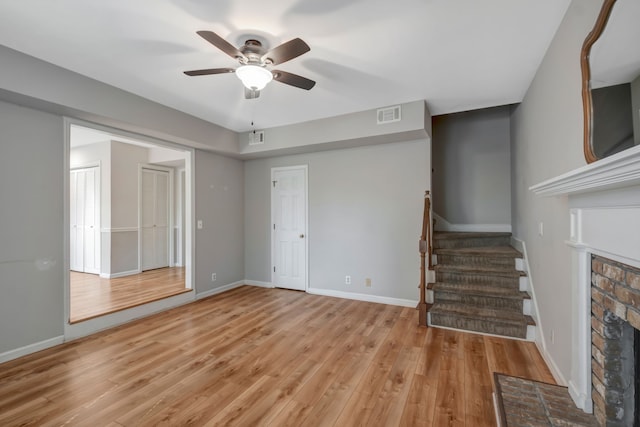 unfurnished living room featuring a brick fireplace, light hardwood / wood-style floors, and ceiling fan