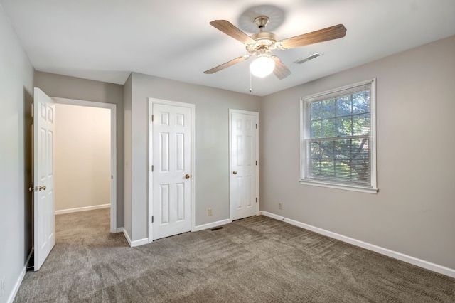 unfurnished bedroom featuring two closets, light colored carpet, and ceiling fan