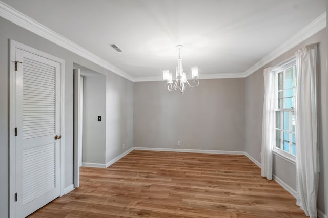 unfurnished dining area featuring ornamental molding, an inviting chandelier, and light wood-type flooring