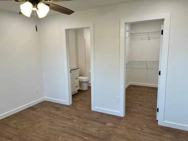 unfurnished bedroom with ceiling fan, ensuite bath, dark wood-type flooring, and a closet