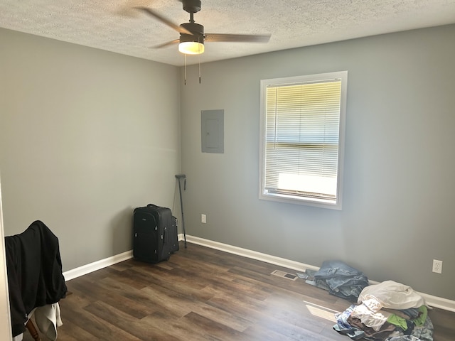 misc room with electric panel, dark hardwood / wood-style floors, a textured ceiling, and ceiling fan