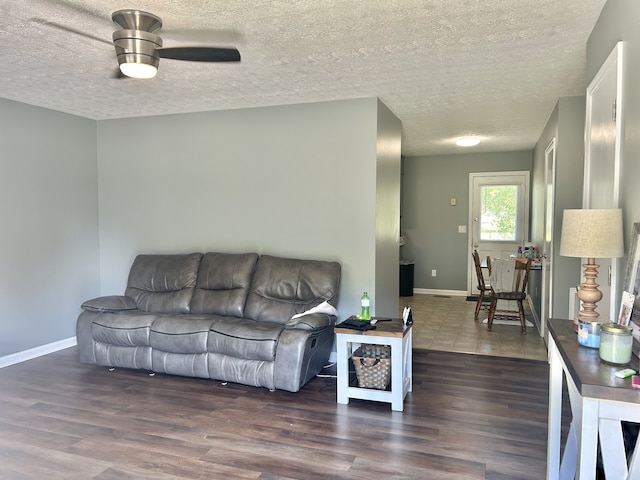 living room featuring ceiling fan, a textured ceiling, and dark hardwood / wood-style flooring