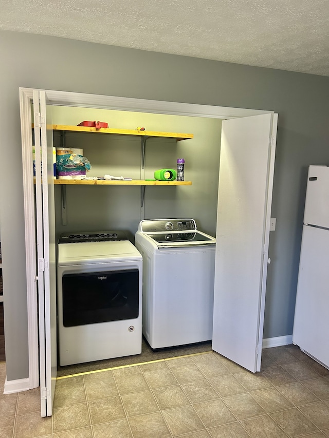 laundry room with light tile patterned floors, washing machine and dryer, and a textured ceiling