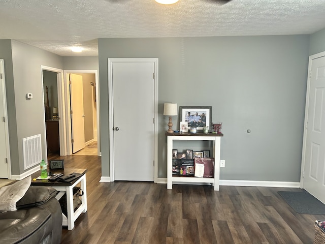 interior space with a textured ceiling and dark hardwood / wood-style flooring