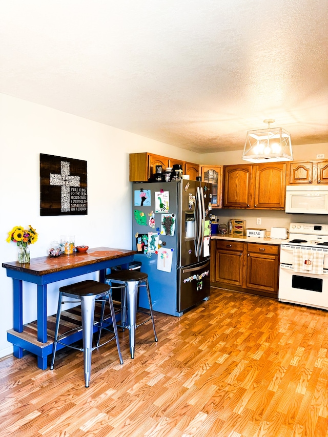 kitchen with light hardwood / wood-style flooring, a textured ceiling, and white appliances