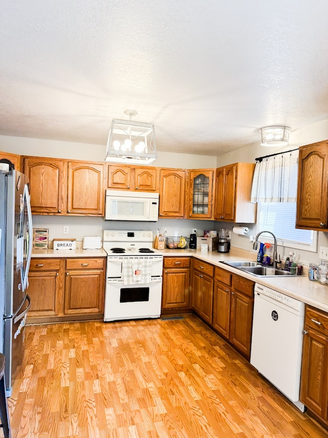 kitchen with sink, light hardwood / wood-style flooring, a textured ceiling, and white appliances