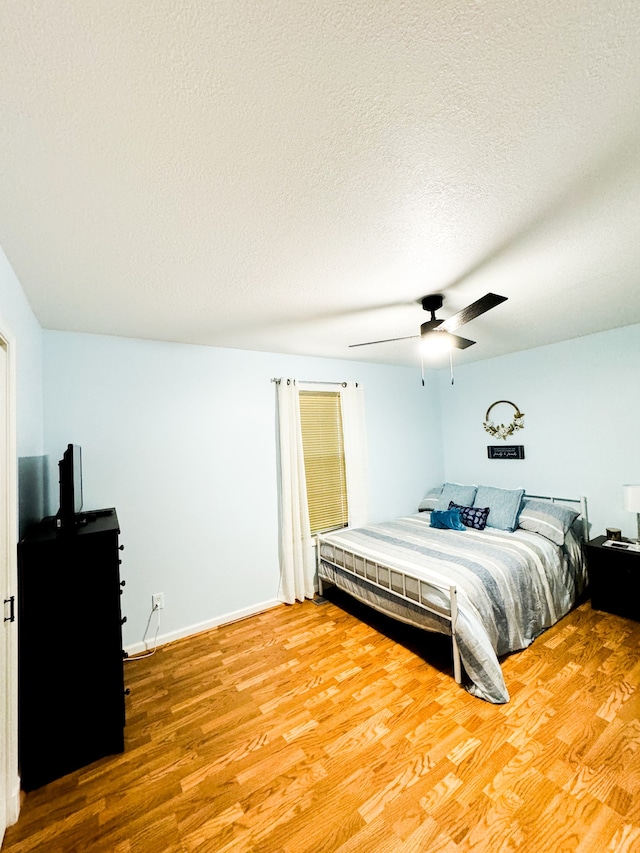 bedroom with a textured ceiling, hardwood / wood-style flooring, and ceiling fan