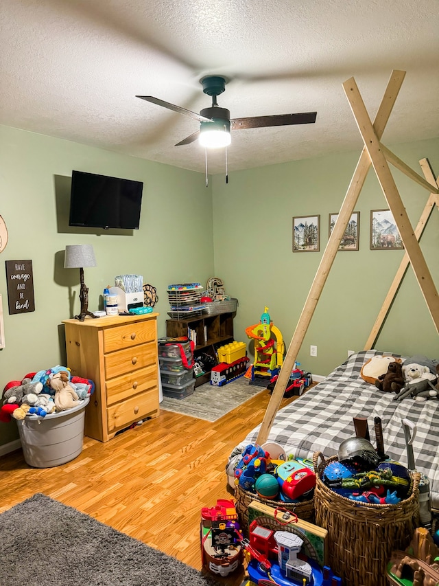 bedroom with ceiling fan, wood-type flooring, and a textured ceiling