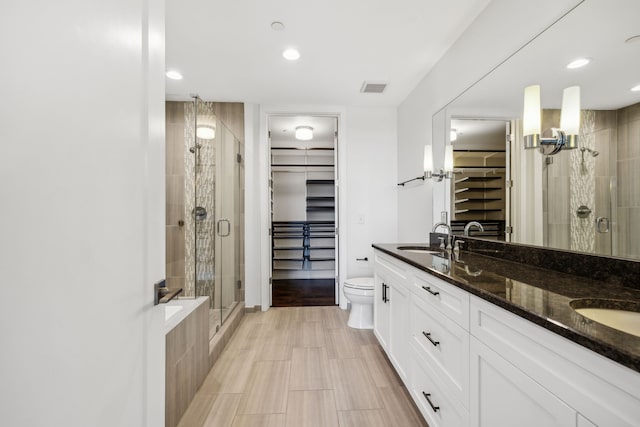 bathroom with a shower with door, vanity, and toilet